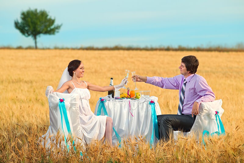 Bride and groom next to wedding table on the wheat field