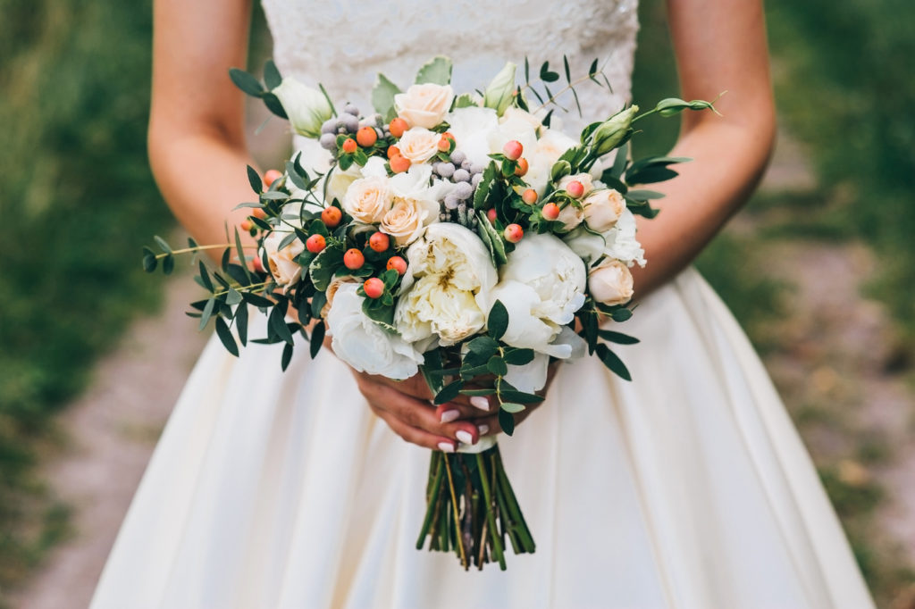 bride holding a bouquet of flowers and berries in a rustic style, wedding bouquet 