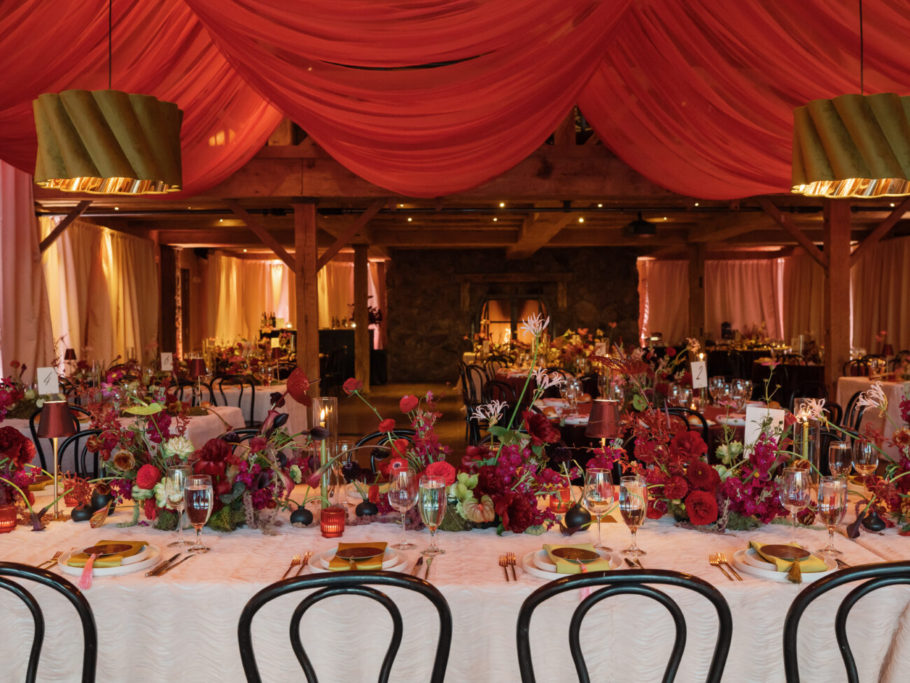 Long reception tables with colorful centerpieces and place settings under warm lighting