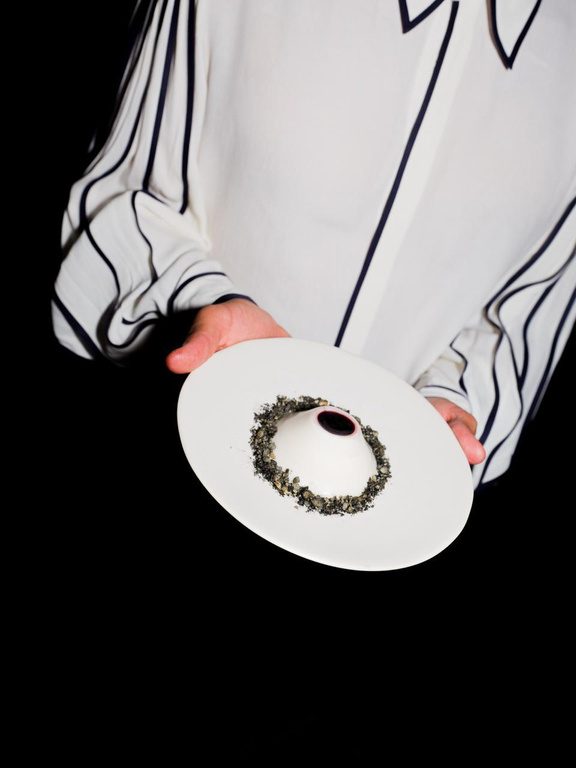 Server presenting a plated dish against a dark background