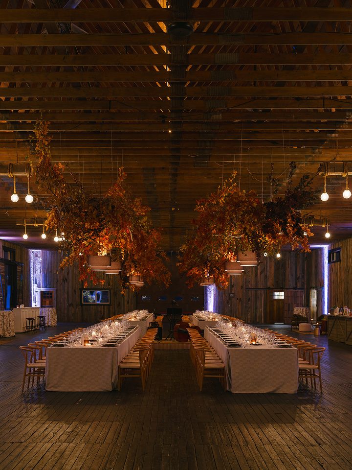 Long banquet tables set inside a timber-framed barn venue