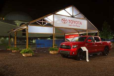 Structure tent lit up at night with branded truck parked outside