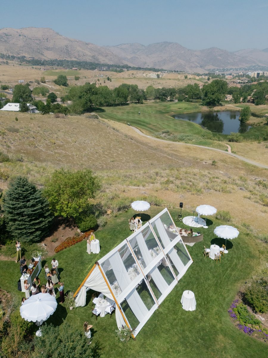Aerial view of a clear-top tent set up on a grass lawn at dusk