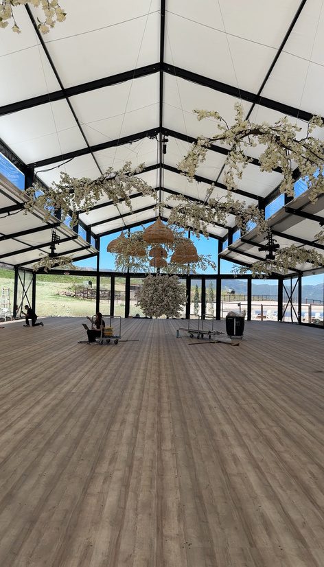 Tent interior with hardwood flooring and hanging floral installation