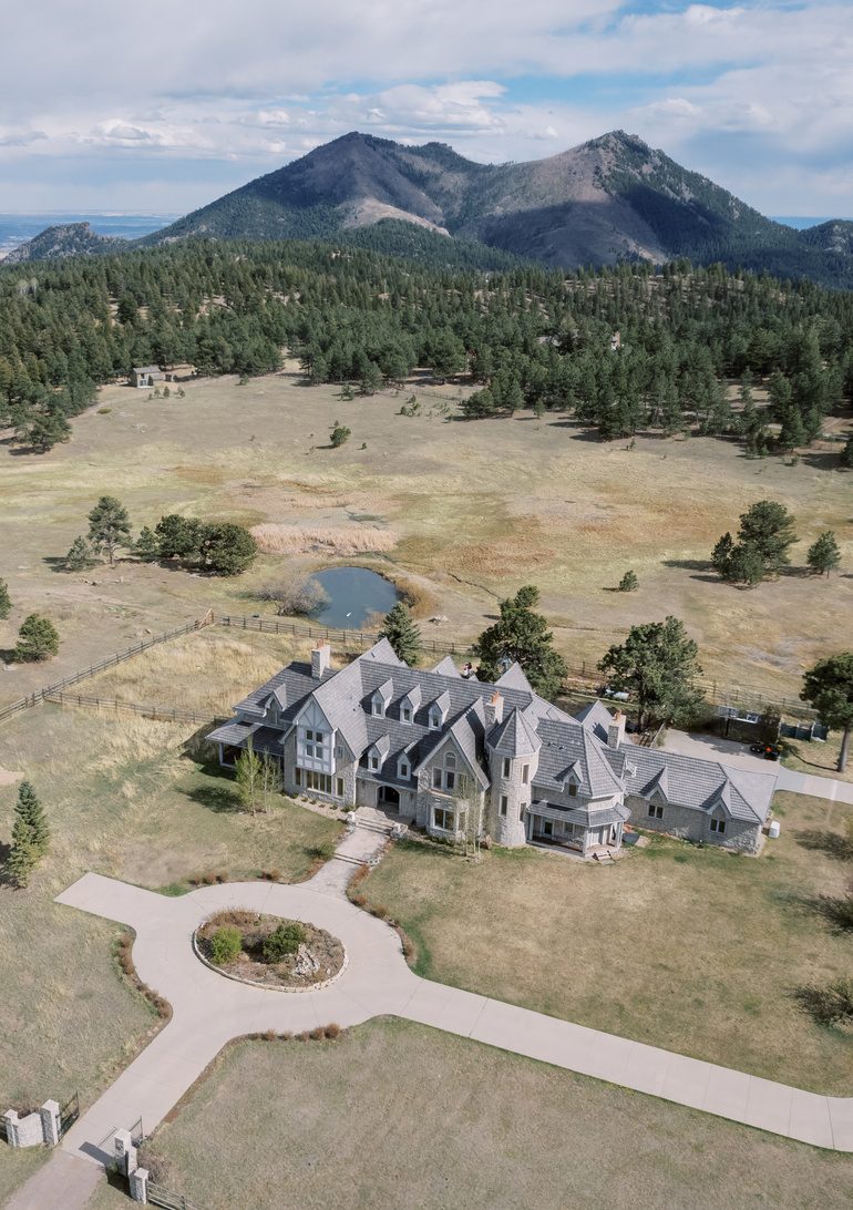 Aerial view of a stone mansion venue surrounded by mountains